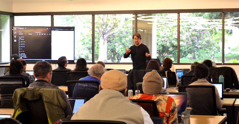 Photo of Fernando teaching seated students at the Python workshop